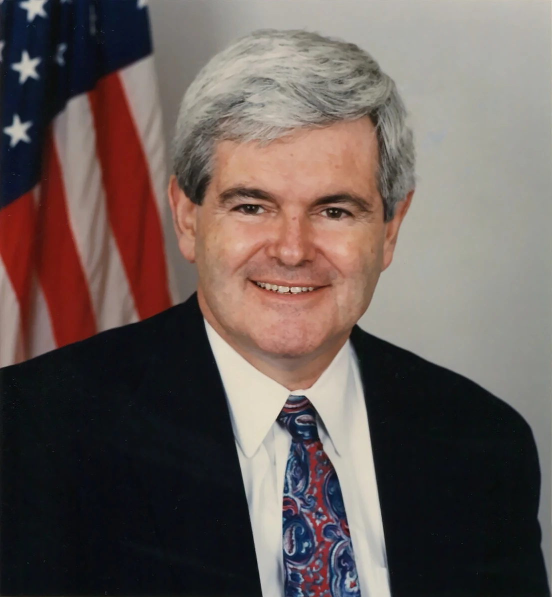 Newt Gingrich in an official congressional portrait with a U.S. flag behind him.